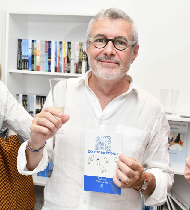 Roland Thimonier l'auteur devant l'objectif avec un livre et un verre à la main
